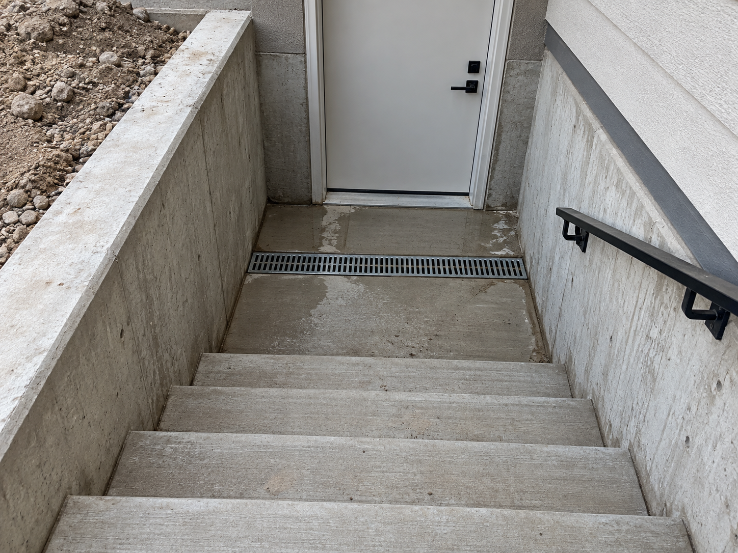 Grated drain at the bottom of concrete walkout basement stairs