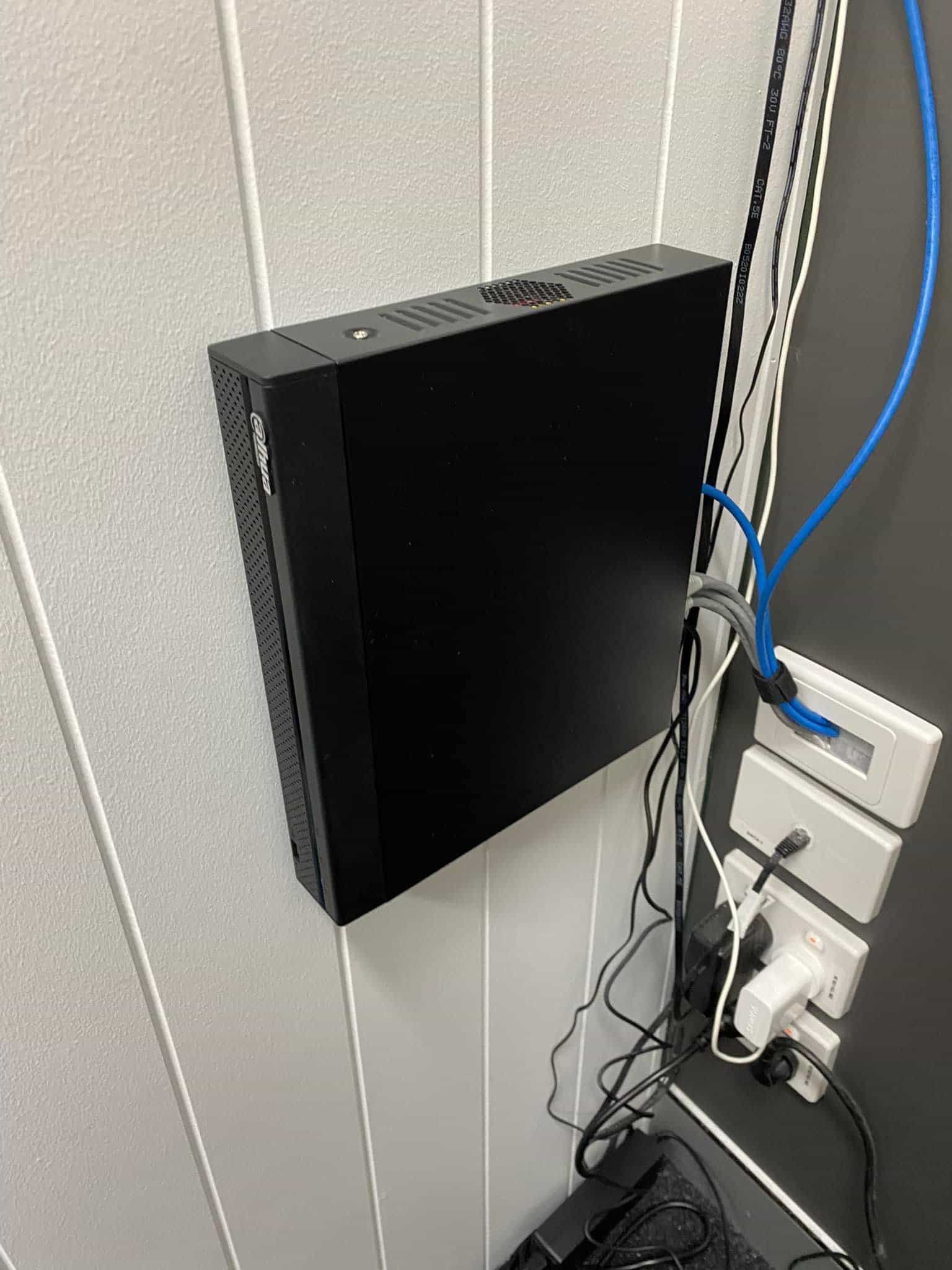 A Black Box is Hanging on a Wall Next to a Bunch of Wires — DGC Tech Solutions In Mareeba, QLD