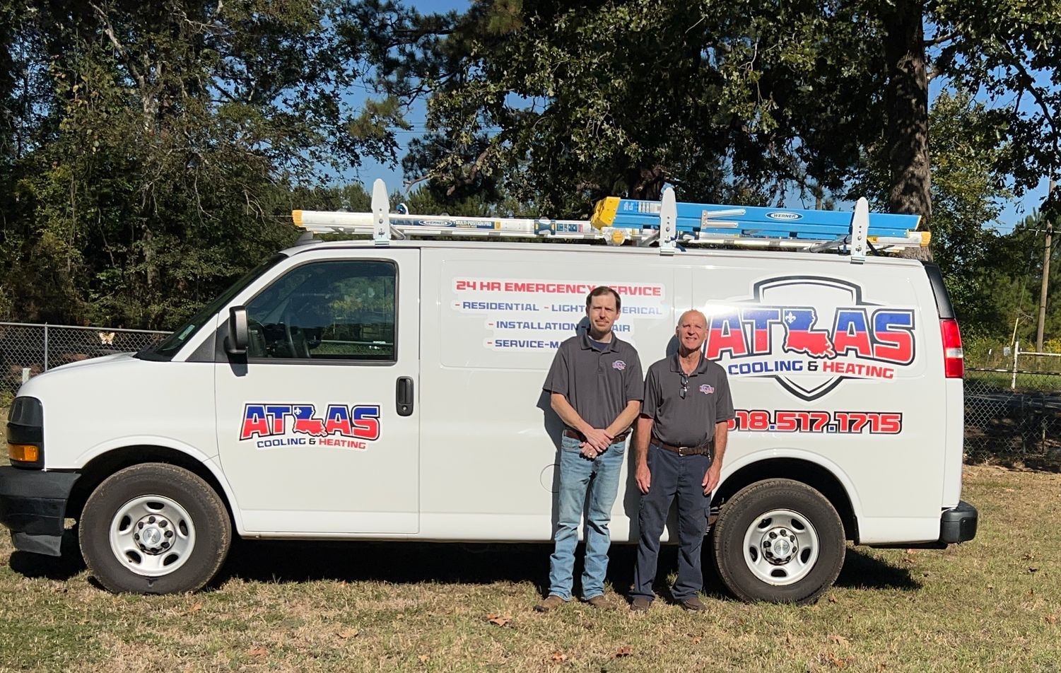 Two men stand beside a white Atlas Plumbing van outdoors.