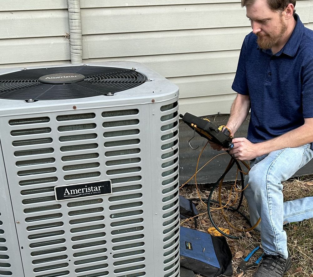 Man using tools to inspect an Ameristar air conditioner unit outdoors near a house.