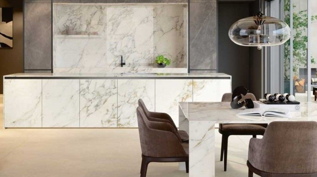 Modern kitchen with marble countertops and island. Dining table with chairs, pendant light.