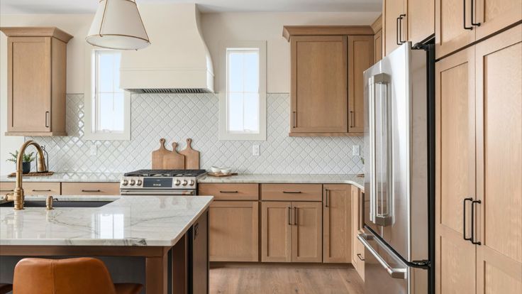 Modern kitchen with light wood cabinets, stainless steel appliances, and white countertops.