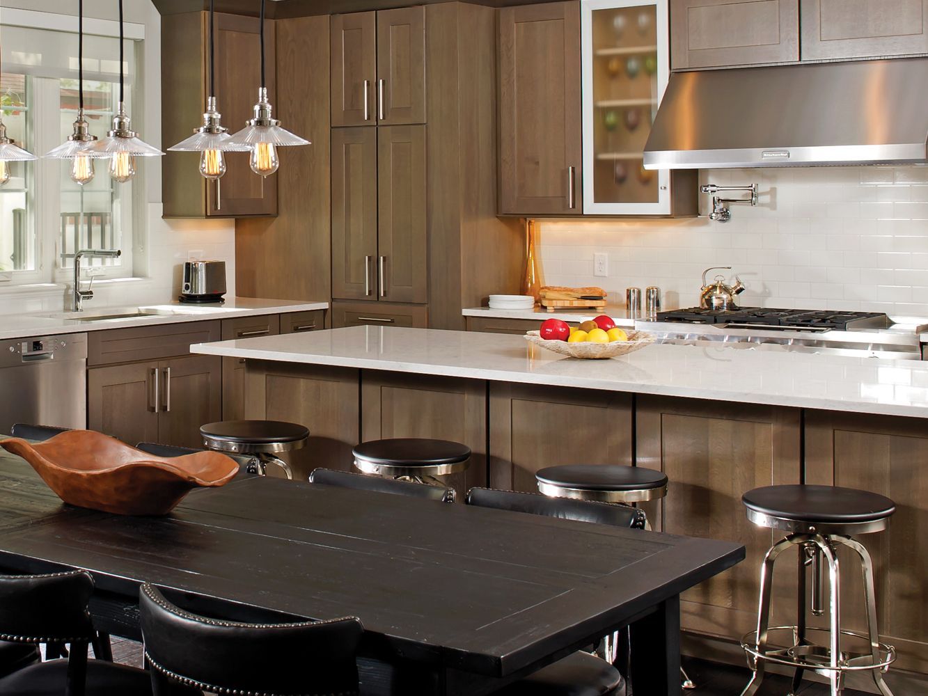 Modern kitchen with dark wood cabinets, white countertops, and a black dining table.