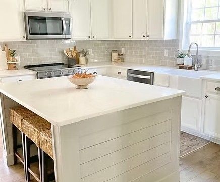 Bright white kitchen with island, breakfast bar stools, and subway tile backsplash.
