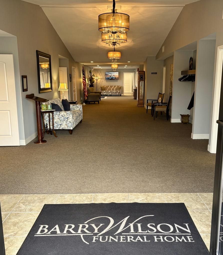 Interior hallway of Barry Wilson Funeral Home with carpet, chandeliers, and seating along the walls