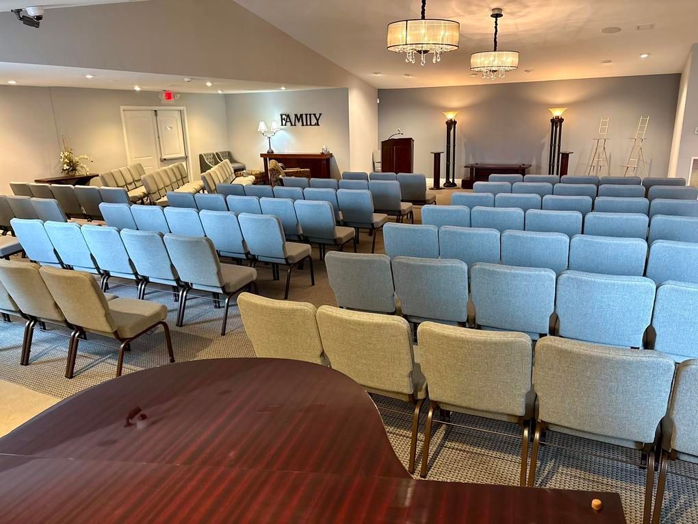 Empty chapel with rows of blue and beige chairs facing the front podium