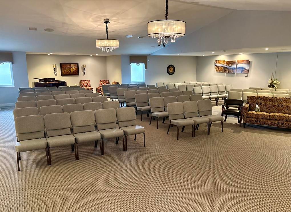 Empty conference room with rows of gray chairs, chandelier lights, and a carpeted floor