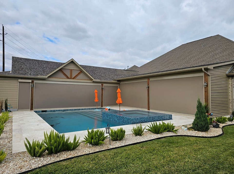 large swimming pool in the backyard of a house with motorized patio shades texas