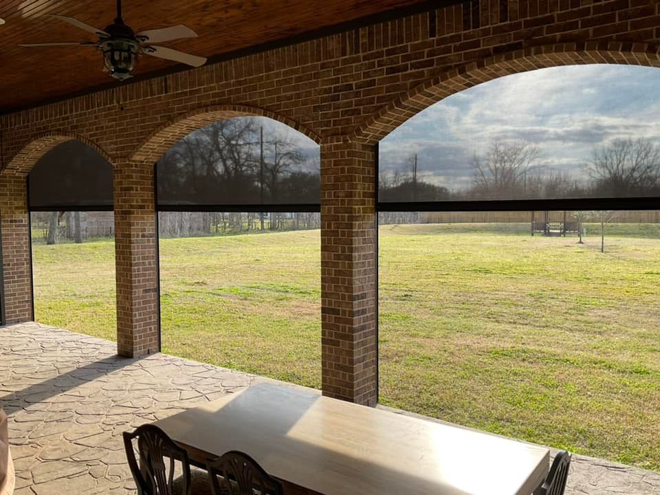 A patio with a table and chairs and a view of a field.