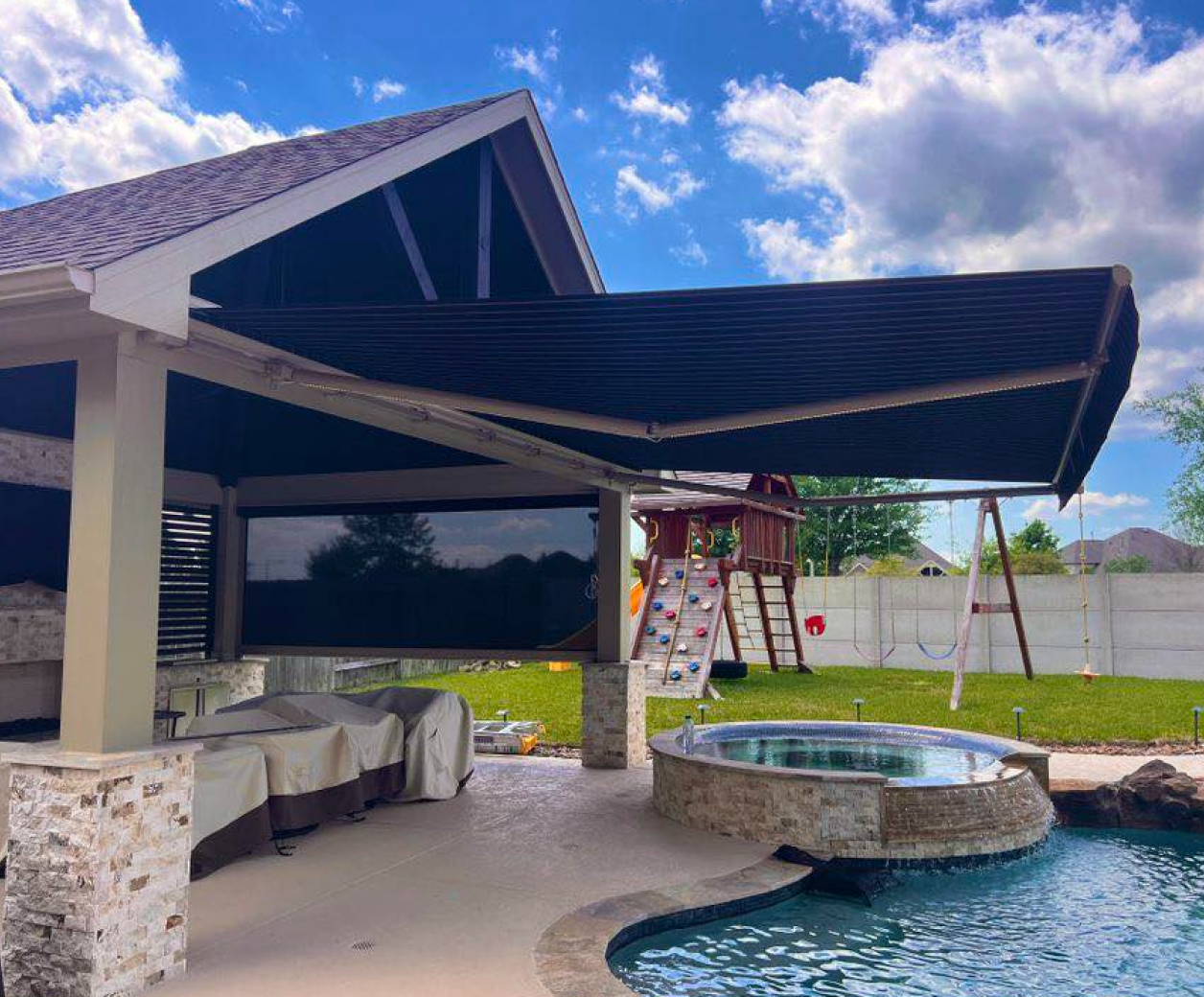 There is a swimming pool in the backyard with a large awning over it.