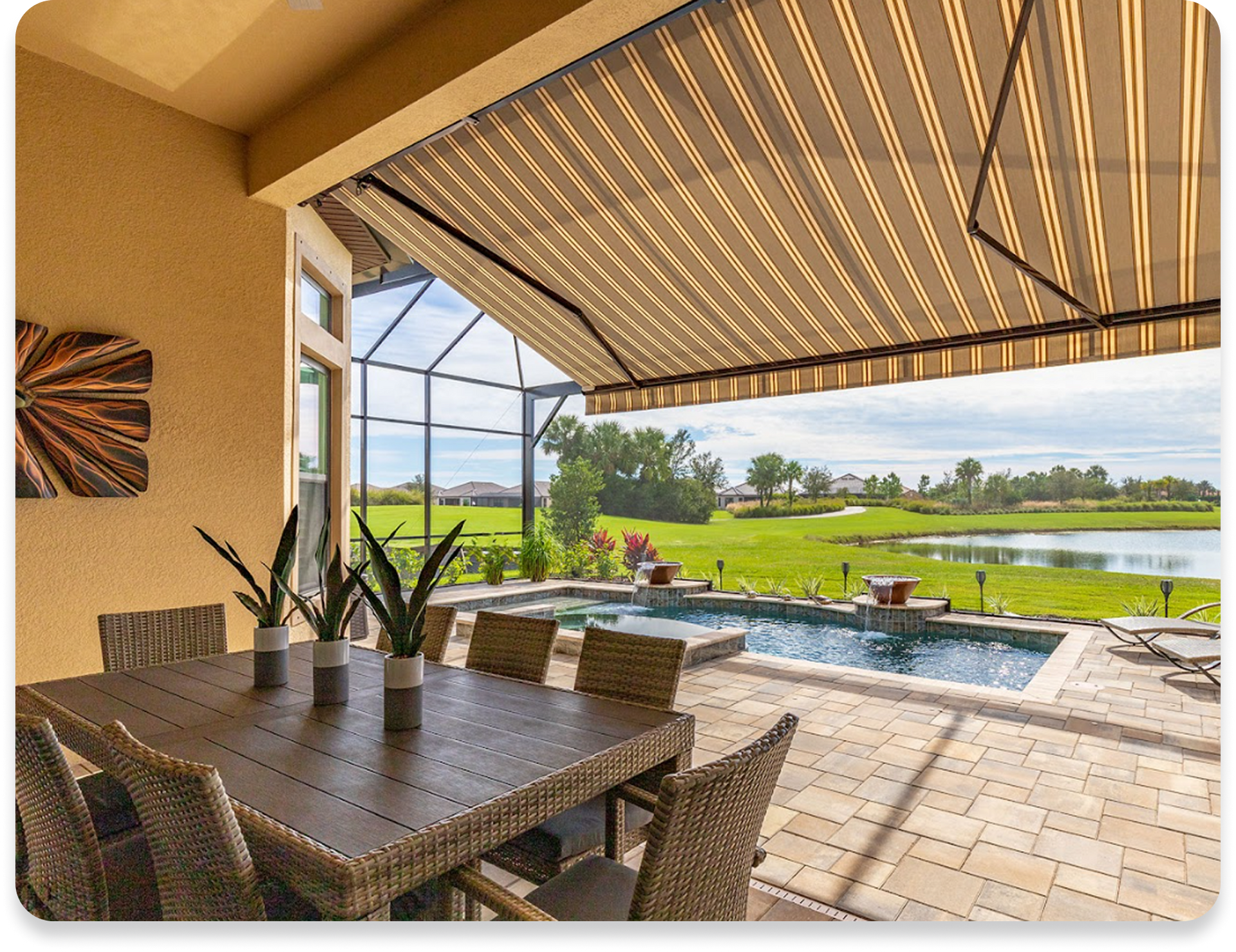 A patio with a table and chairs and a striped awning over it.