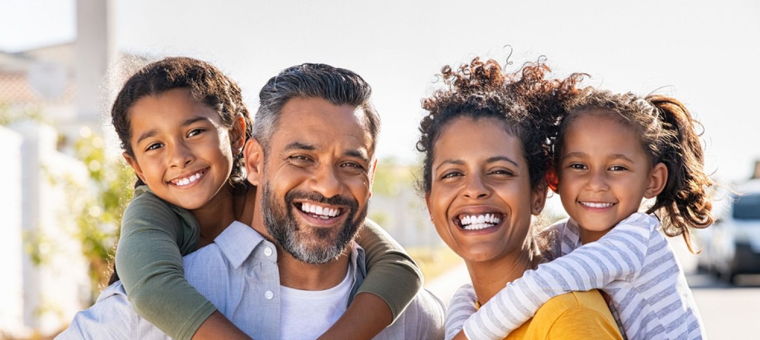 Smiling family hugging outdoors in bright sunlight