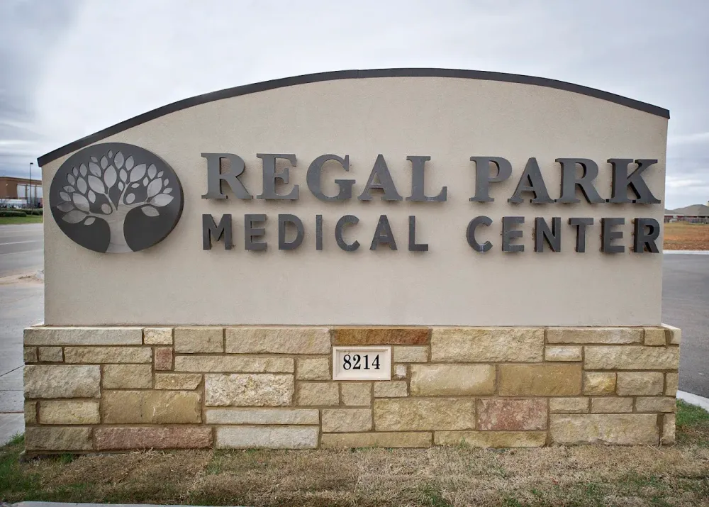 Regal Park Medical Center sign on stone wall with tree logo, beige background, and small address plaque