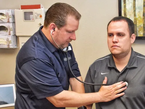 Doctor using a stethoscope to examine a man in a clinic office