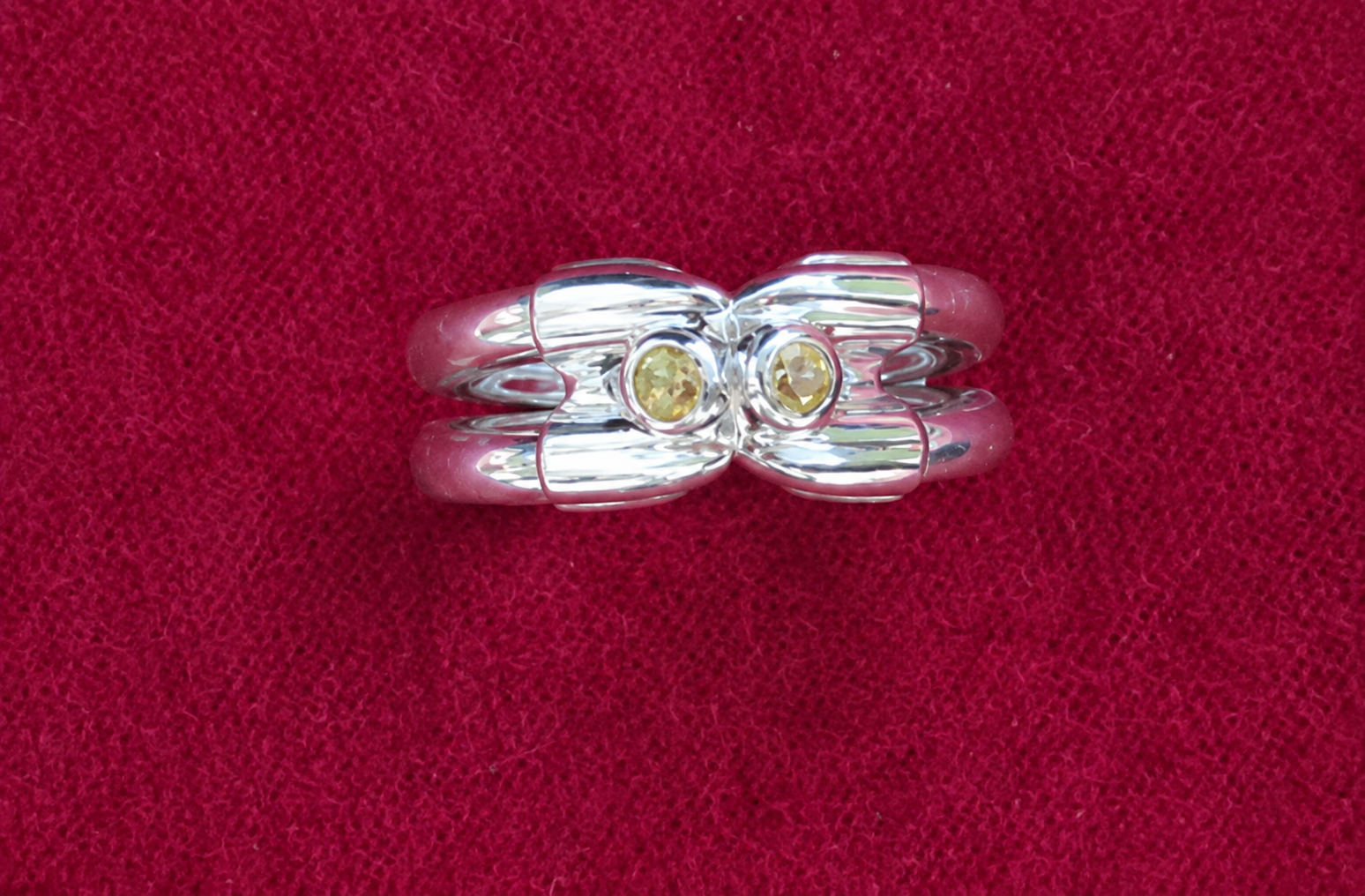 Bague en argent ornée de deux pierres précieuses transparentes sur un fond de velours rouge
