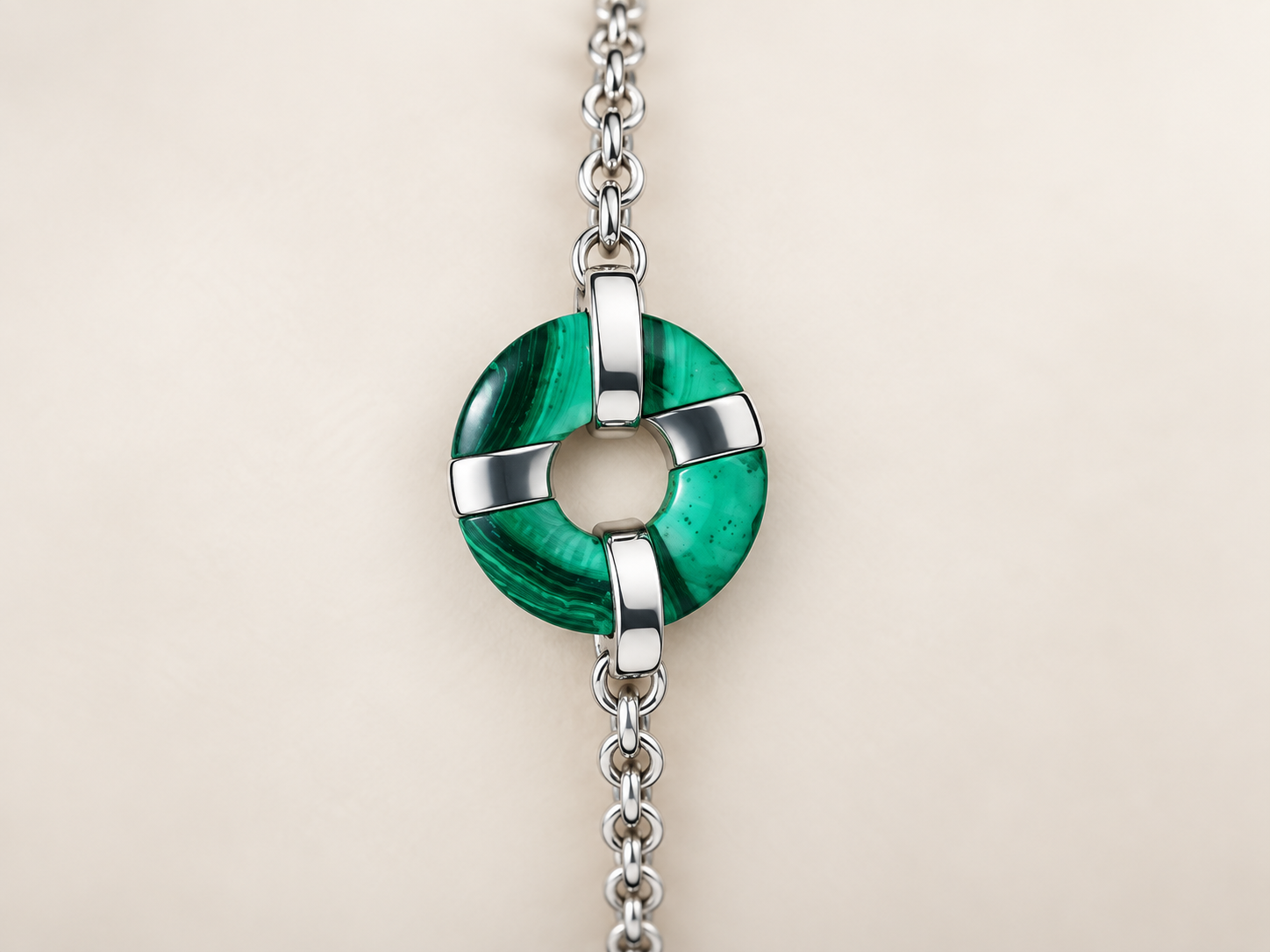 Pendentif circulaire vert et argenté sur une chaîne, sur fond clair