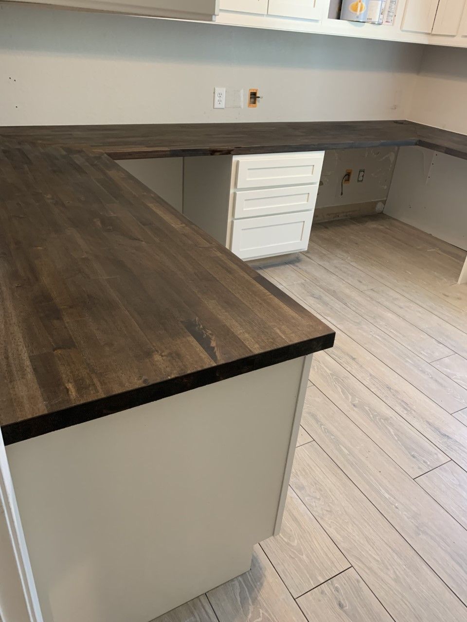 A kitchen with a wooden counter top and white cabinets.