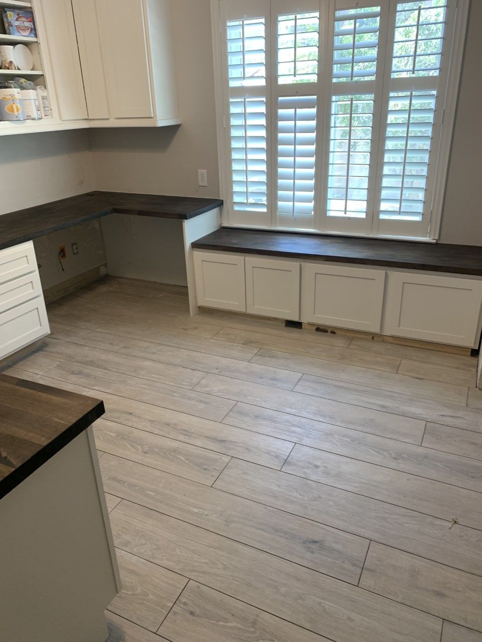 A kitchen with a bench in the window and shutters on the windows.