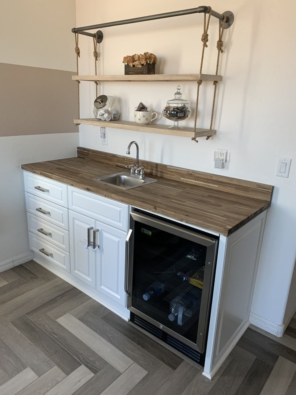 A kitchen with a sink , refrigerator , and shelves.