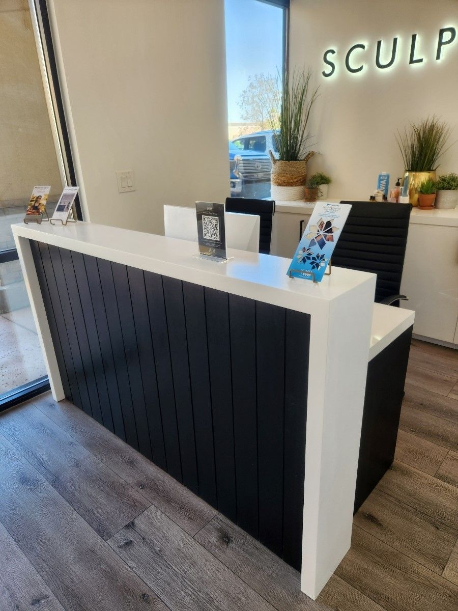 A black and white reception desk in a room with a sign that says sculpt