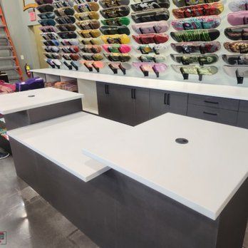 A counter in a store with a lot of skateboards on the wall behind it