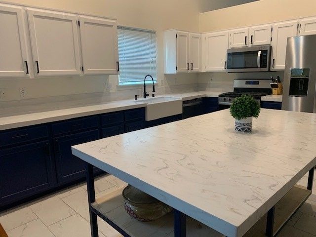 A kitchen with blue cabinets and white counter tops