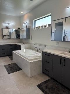 A bathroom with a tub , sink and mirrors.