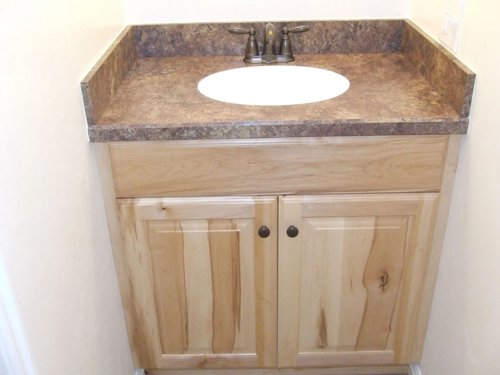 A bathroom sink with wooden cabinets and a granite counter top.