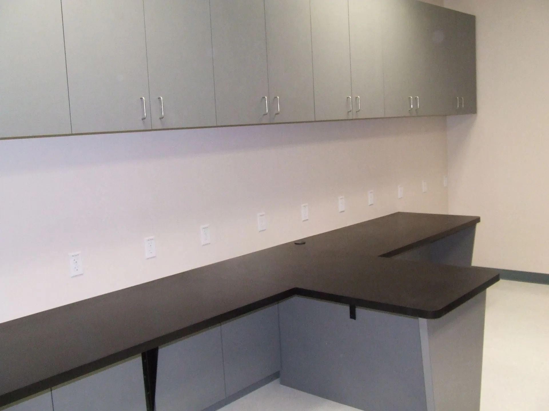 An empty room with a desk and cabinets on the wall.
