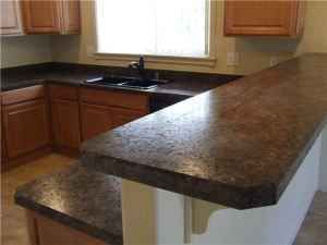A kitchen with granite counter tops, wooden cabinets, a sink and a window.