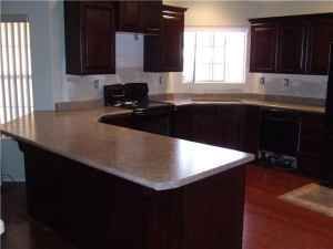 A kitchen with brown cabinets, granite counter tops, a stove, and a window.
