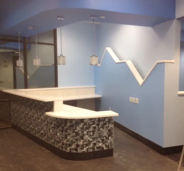 A reception area with blue walls and a white counter.