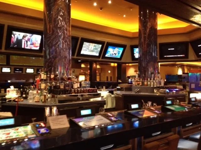 A bar in a casino with a lot of tv screens.