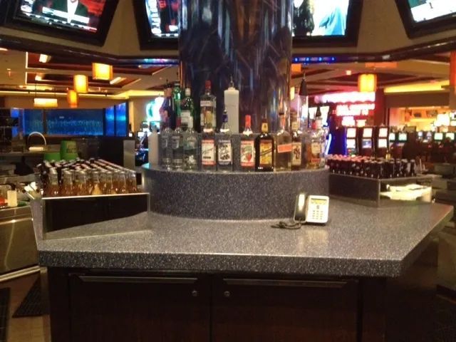 A bar in a casino with bottles of liquor on it.