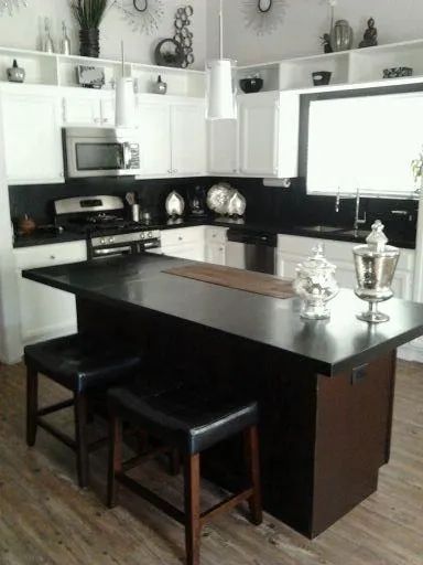 A kitchen with white cabinets and black counter tops.