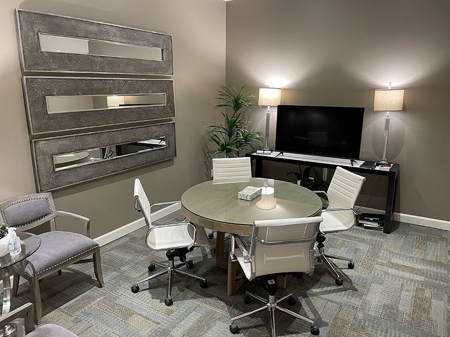 A conference room with a round table and chairs and a flat screen tv.