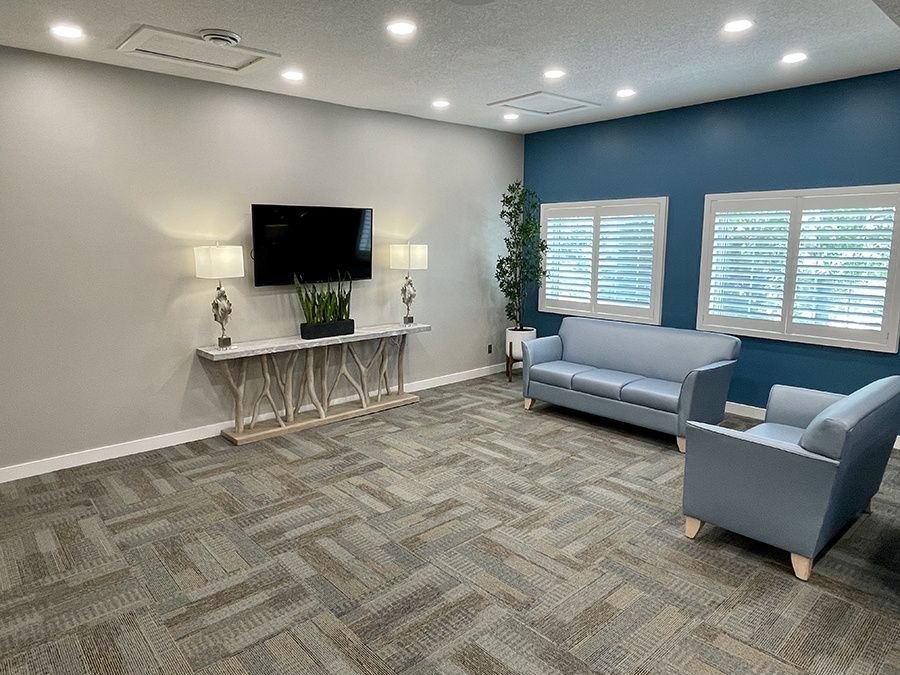 A living room with a couch , chairs , and a flat screen tv.