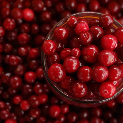 Pot rode jam met wit etiket, naast meloen, cranberry's en specerijen.