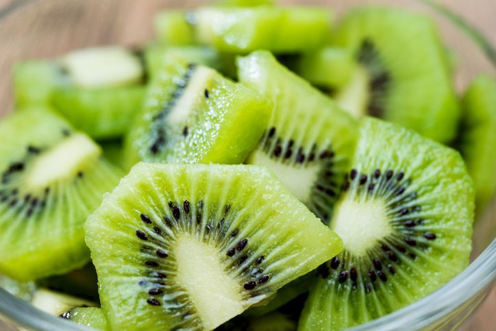 Gesneden kiwi in een glazen kom, met groen vruchtvlees, zwarte pitjes en witte kern.