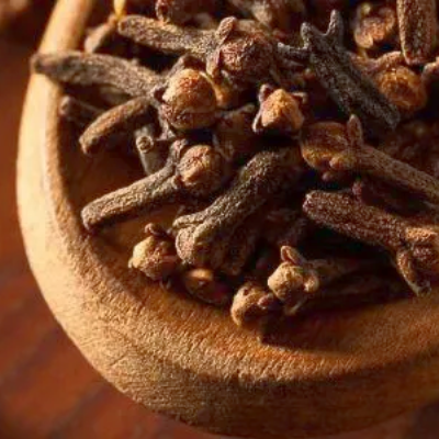 Gedroogde kruidnagels in een houten schepje, close-up.