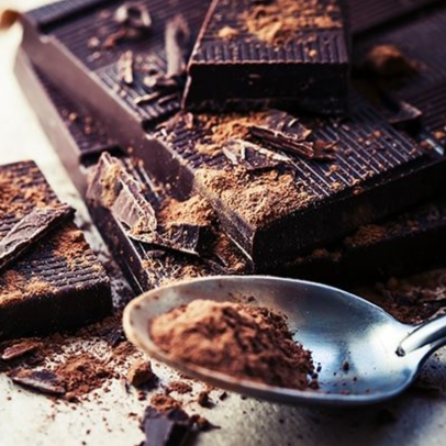 Pure chocoladerepen en cacaopoeder op een witte ondergrond, met een lepeltje cacao.