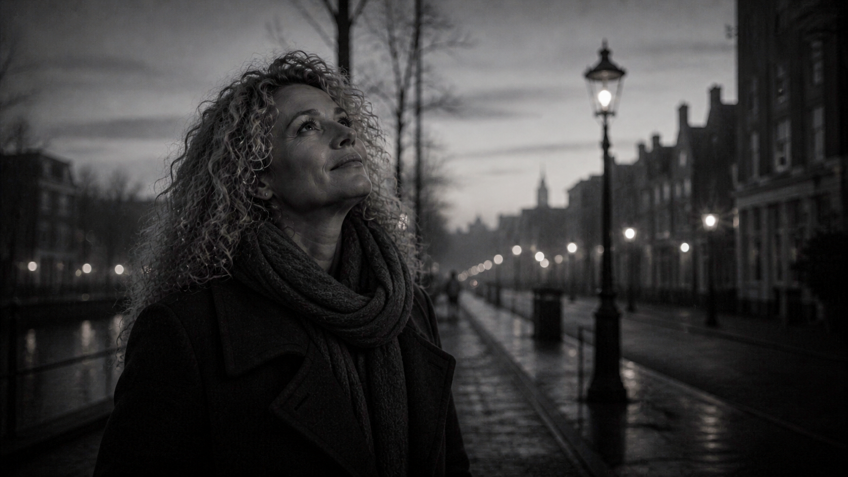 Vrouw staat ’s nachts op een regenachtige stadsstraat en kijkt omhoog, vlak bij gloeiende straatlantaarns en weerspiegelingen in het kanaal