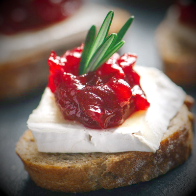 Voorgerecht met brie en cranberry op geroosterd brood, gegarneerd met rozemarijn.