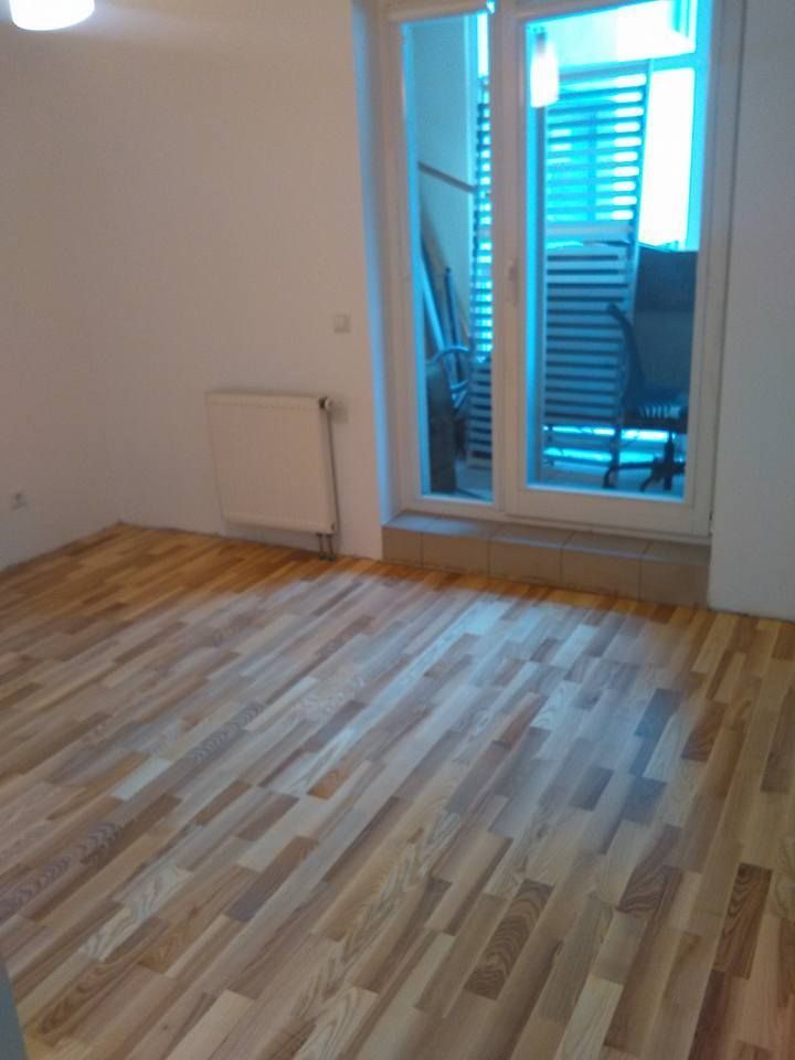 Kambarys su medinėmis grindimis ir stumdomomis stiklinėmis durimis