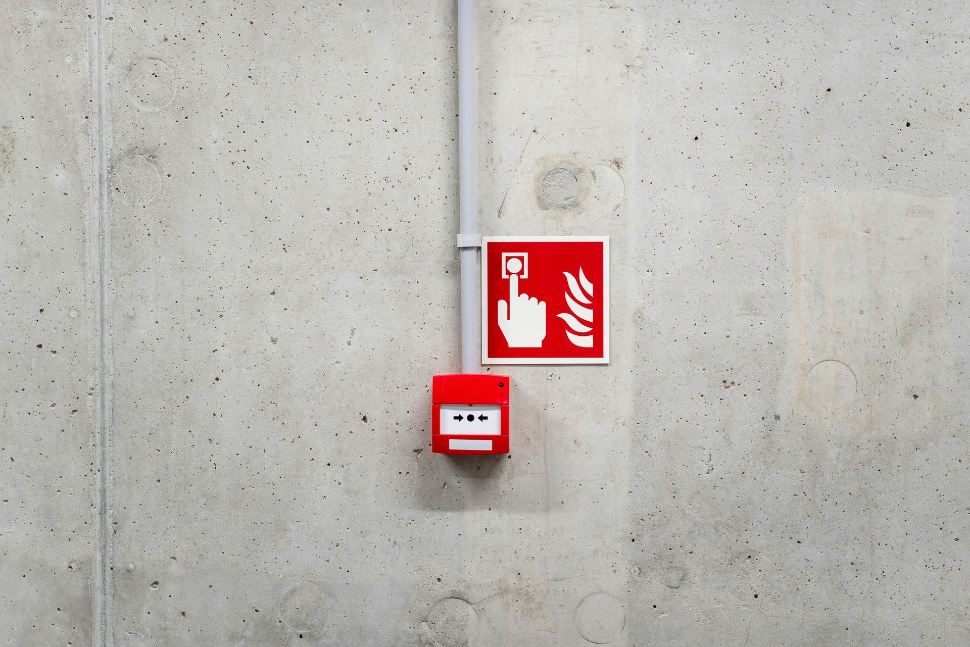 A red fire alarm box is attached to a concrete wall