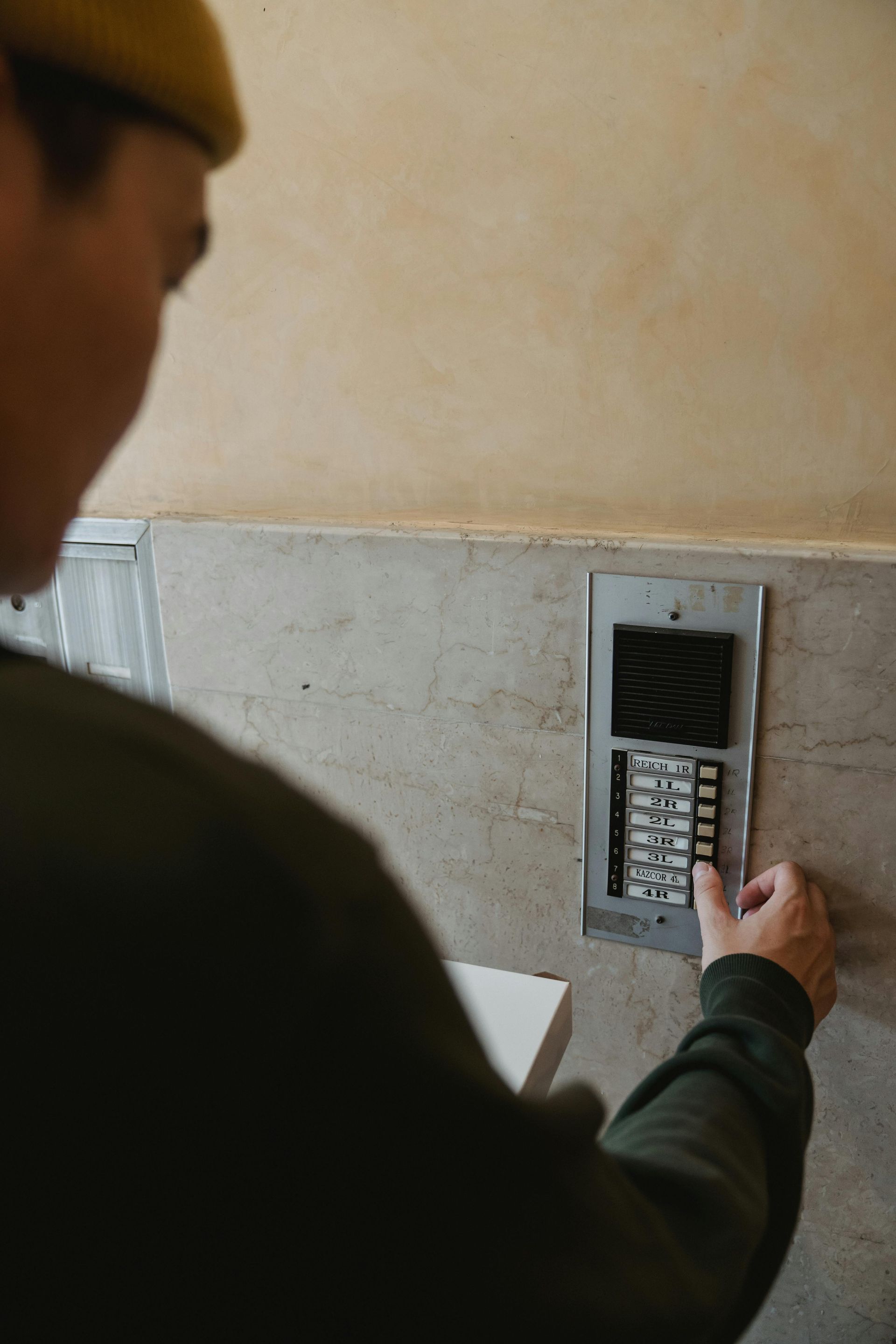 A man is pressing a button on a wall.