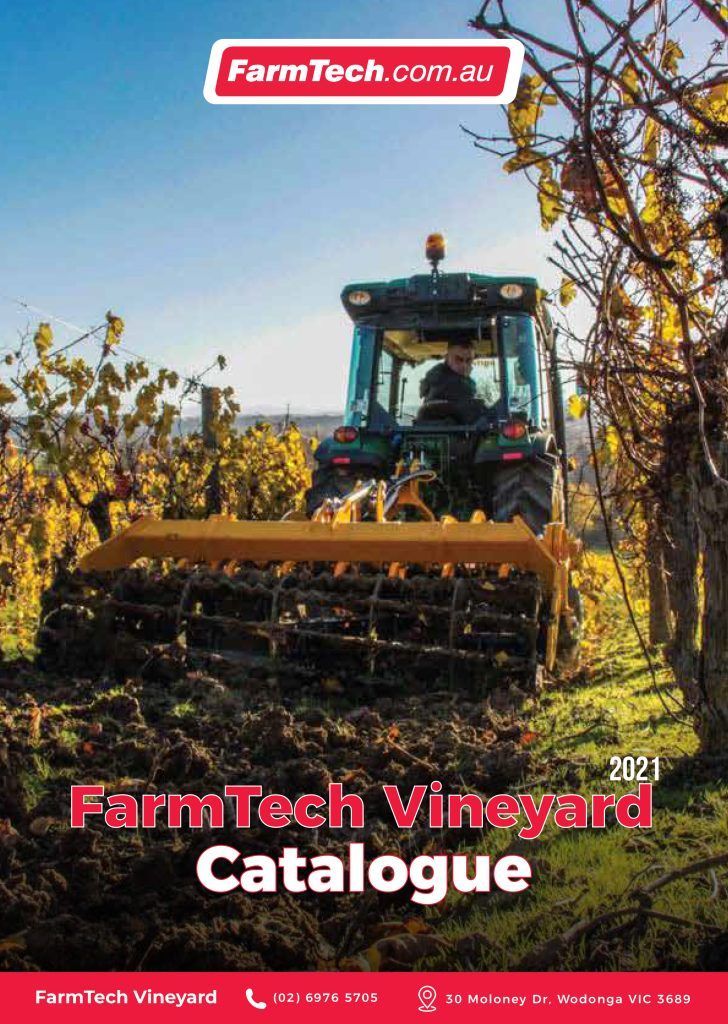 A man is driving a tractor through a vineyard.