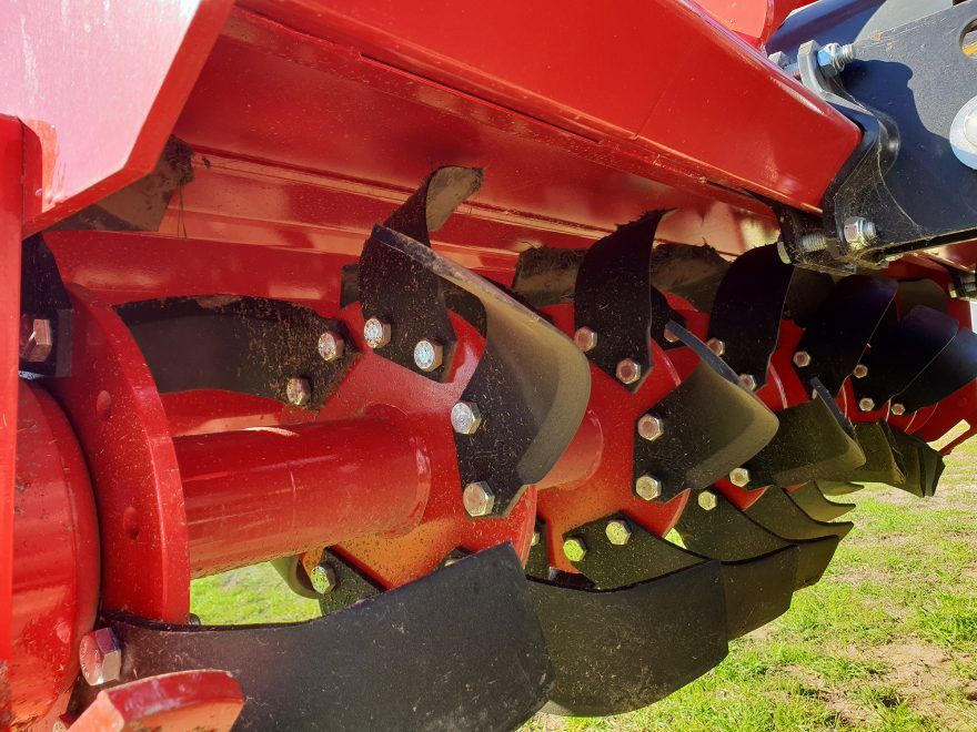 Side view of a yellow disc tiller in a field.