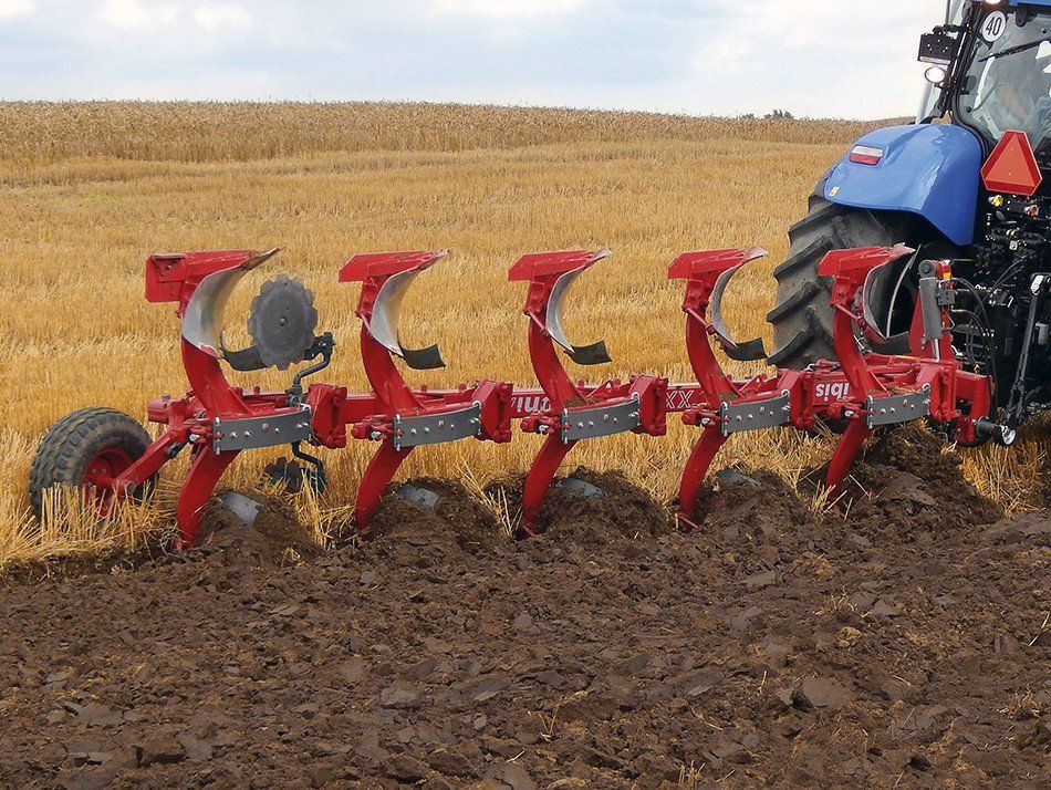A tractor is plowing a field with a disc tiller attached to it.