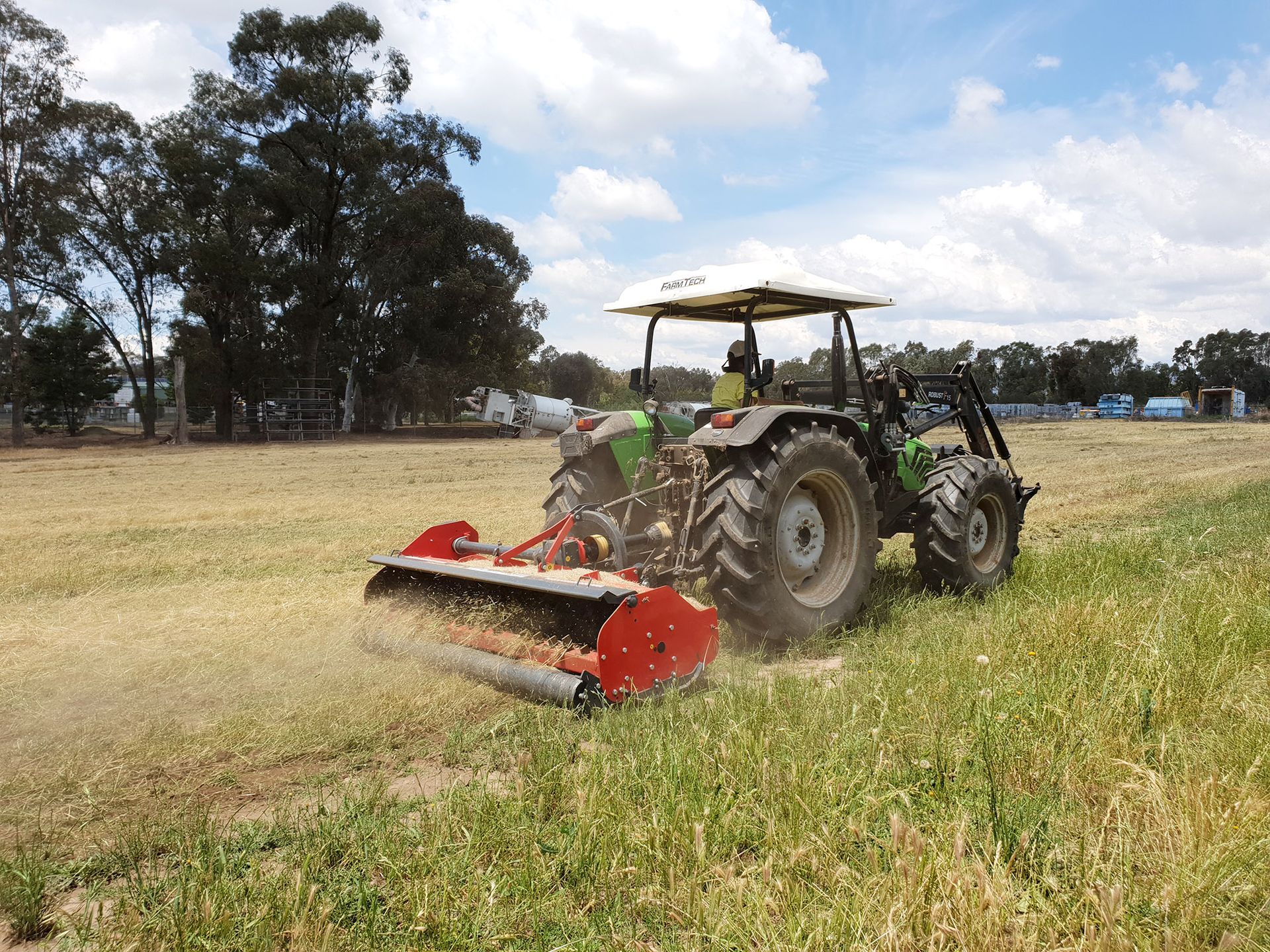 A green and red tractor is parked in a field